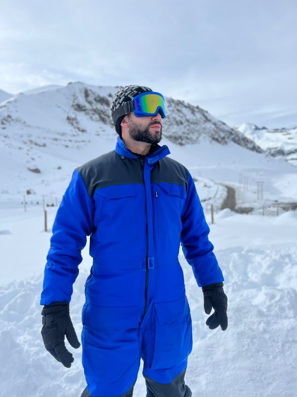 MAUG de macacão azul e óculos de neve em uma montanha nevada